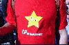 En person iförd en röd t-tröja med CP-arméns logotype (en gul stjärna med skelande ögon) och texten CP-magasinet. (Klicka på bilden för att se en större bild)