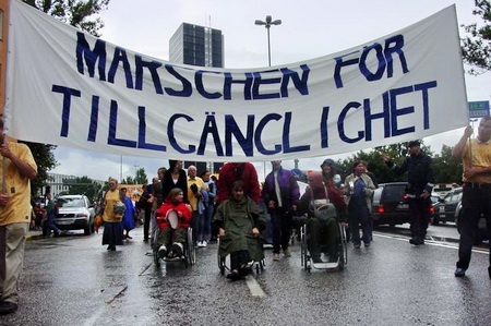 Bild från Marschen för tillgänglighet 2003; täten på marschtåget med Jonas Franksson och Hans Filipsson i regnkläder. Foto: Ilias Bennani Bild från Marschen för tillgänglighet 2003; täten på marschtåget med Jonas Franksson och Hans Filipsson i regnkläder. Foto: Ilias Bennani